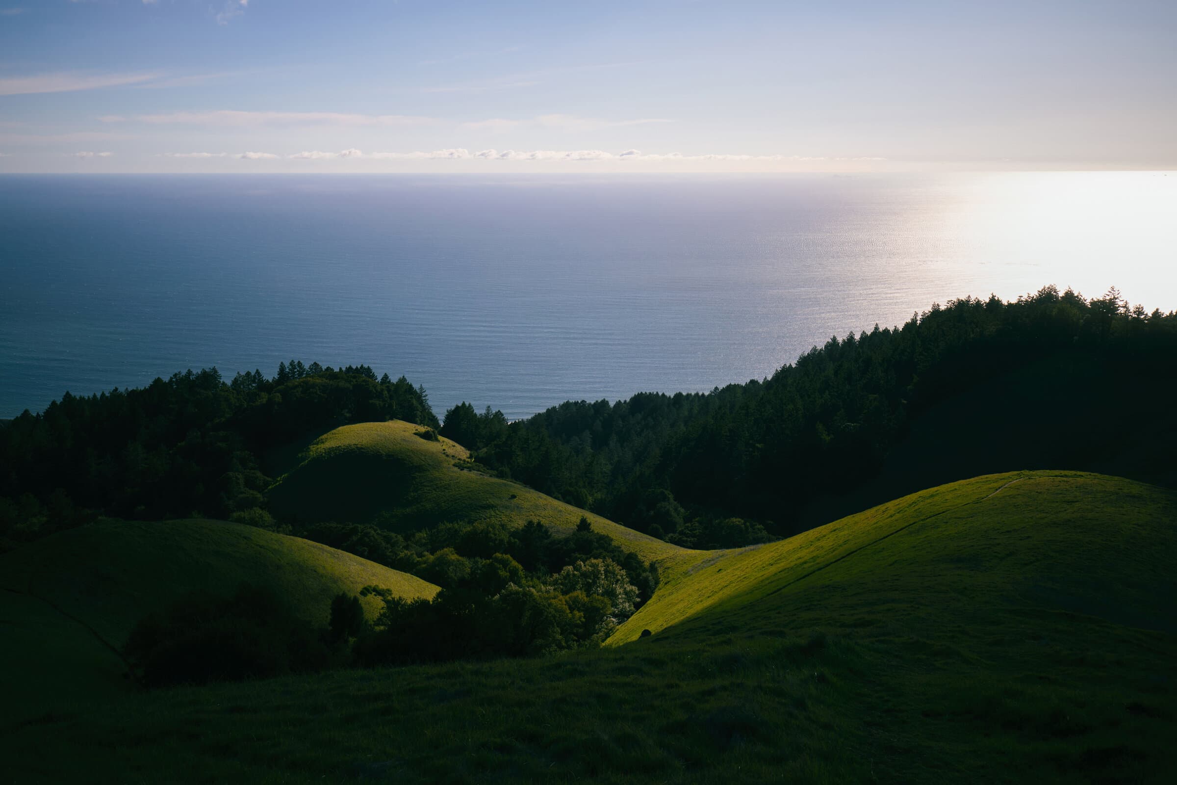 Green coastal hills above the Pacific Ocean, fine art photograph by Jason Bowman