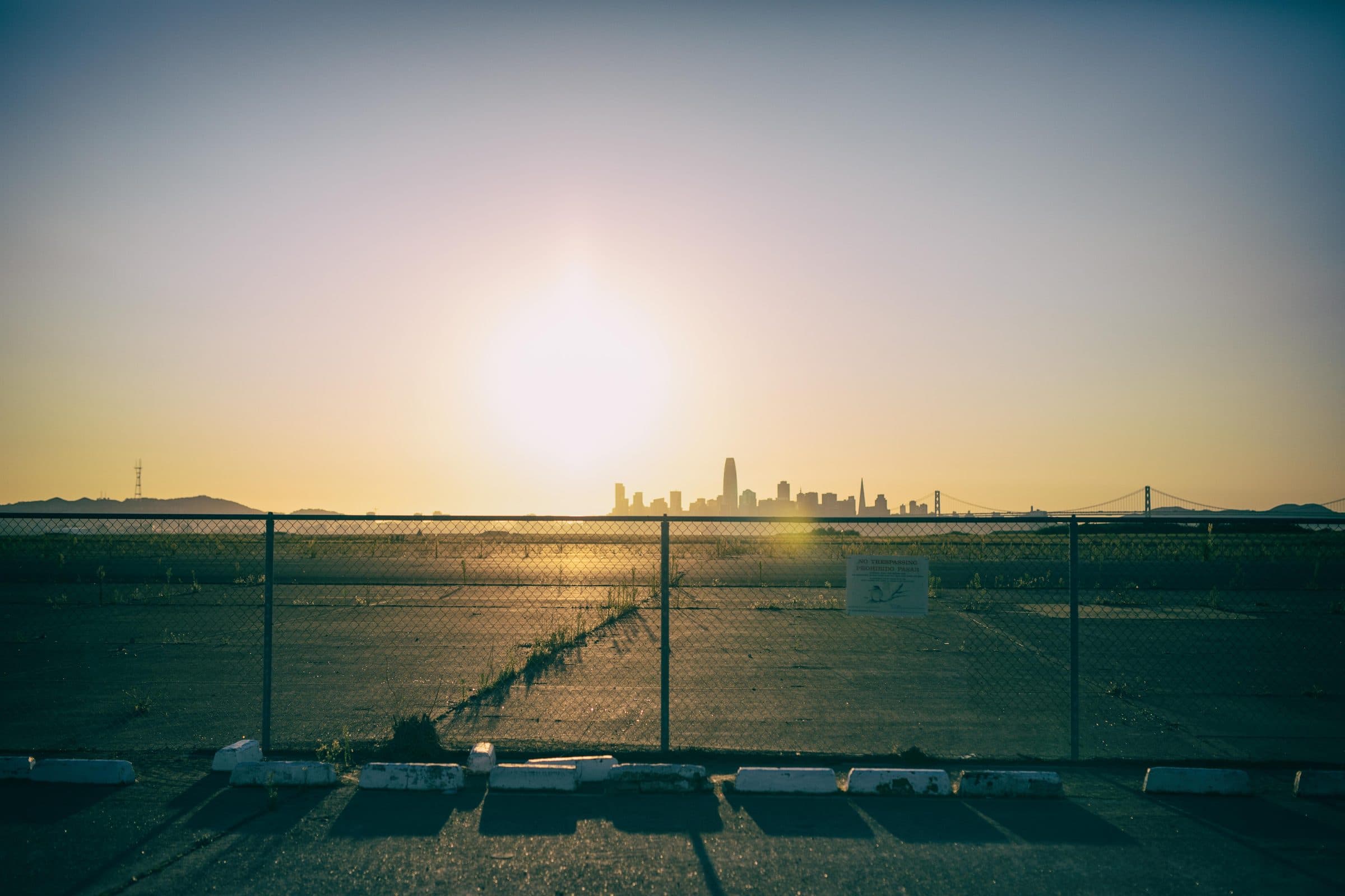 San Francisco skyline at sunset beyond a chain-link fence, fine art photograph by Jason Bowman