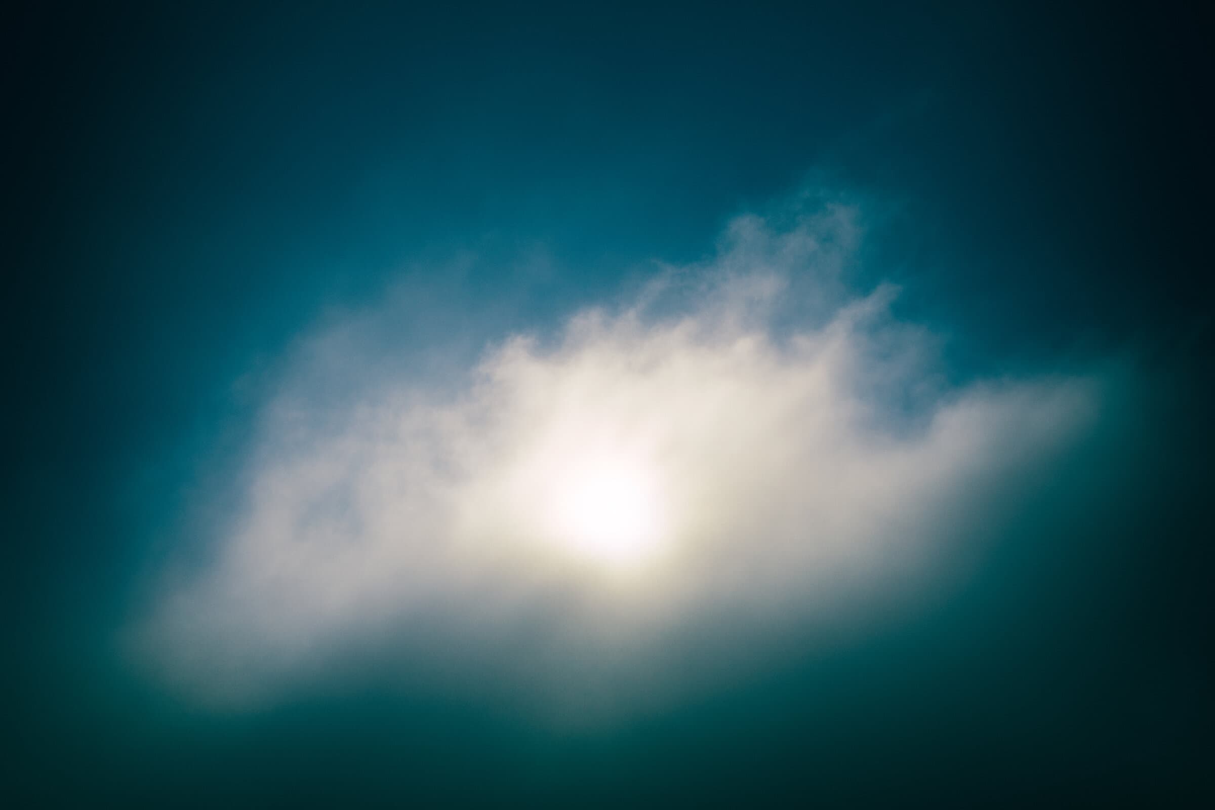 Sun glowing behind a cloud at dusk, fine art photograph by Jason Bowman